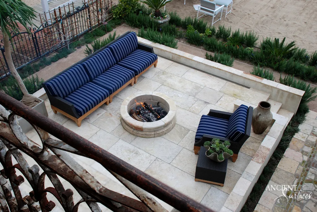 Reclaimed Tunisian limestone terrace paving around a round limestone fire pit, seen from above through a wrought iron balcony railing