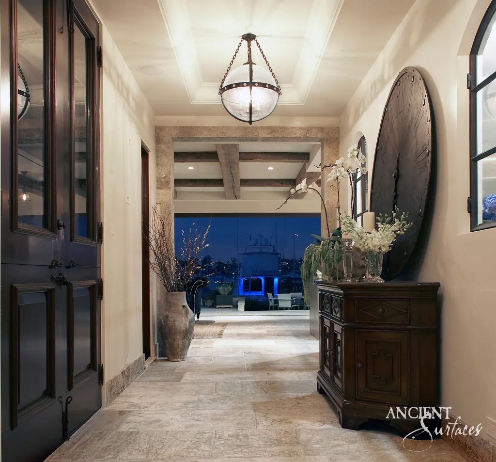 Reclaimed Dalle de Bourgogne limestone hallway at dusk leading through a stone doorway to the water