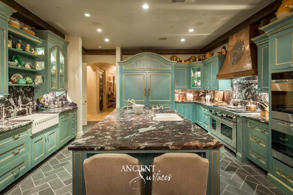 Kitchen island topped in reclaimed Noir Saint Laurent marble with white veining, above a herringbone floor of reclaimed French limestone and teal cabinetry